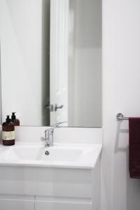 een badkamer met een witte wastafel en een spiegel bij Island Cottages in Nelly Bay