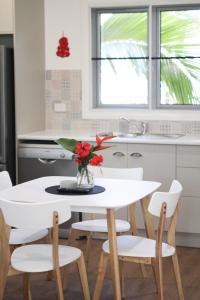 een witte tafel met een vaas met bloemen erop in een keuken bij Island Cottages in Nelly Bay