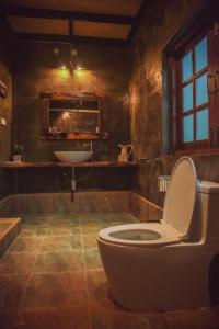 a bathroom with a toilet and a sink at Tree Roots Retreat in Rayong