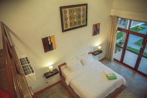 a bedroom with a white bed and a window at Tree Roots Retreat in Rayong