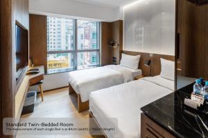 una camera d'albergo con due letti e una scrivania di The OTTO Hotel a Hong Kong