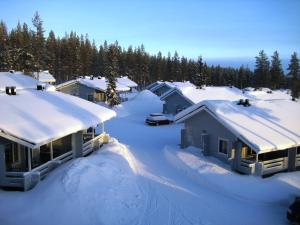 un groupe de maisons recouvertes de neige et d'arbres dans l'établissement Kuerkaltio Holiday Village, à Äkäslompolo