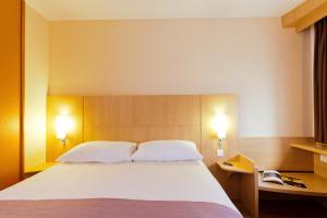 una camera da letto con un grande letto bianco con due cuscini di ibis Paris la Défense Esplanade a Courbevoie