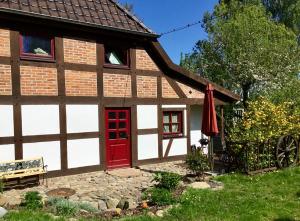 eine rote Tür in einem weißen Gebäude mit einem roten Fenster in der Unterkunft Fachwerkhaus 4 Birken in Rumpshagen