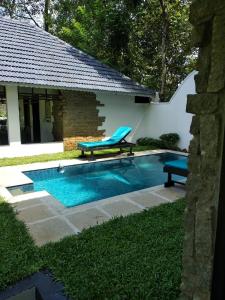 una piscina con un banco y una silla al lado en Mayas Beach House, en Mararikulam