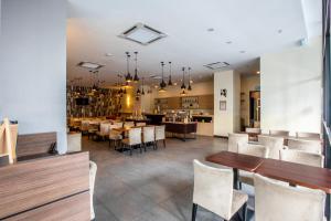 un restaurante con mesas de madera y sillas blancas en The Leverage Business hotel (Skudai) en Johor Bahru