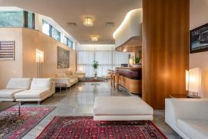 un soggiorno con mobili bianchi e pianoforte di Hotel Polo a Rimini