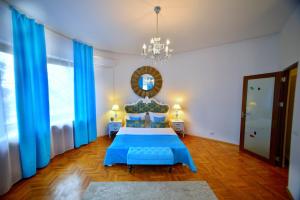 a bedroom with a blue bed and a chandelier at Casa Negustorului in Deva