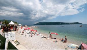 un grupo de personas en una playa con el océano en Nikic Apartments, en Herceg-Novi