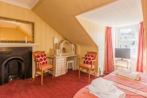 een slaapkamer met een bed, 2 stoelen en een spiegel bij Menzies Guest House in Edinburgh