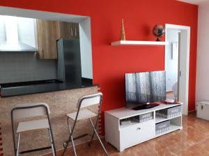 プエルト・デル・カルメンにあるapartamento MAKTUBの赤い壁のキッチン、椅子2脚、テレビが備わります。
