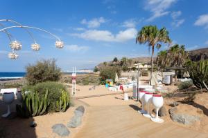 a boardwalk leading to a beach with palm trees at Bungalow Palm Mar with pool and garden in Arona