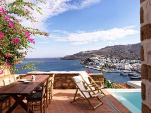 Patmos Eye Traditional Luxury Villas في سكالا: طاولة وكراسي على فناء مطل على المحيط