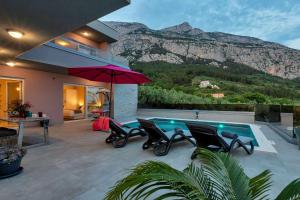 a house with a swimming pool with chairs and an umbrella at Holiday home Villa Astra in Makarska