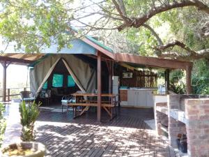 
a patio area with a table, chairs, and a tent at Bushbuck Camp in Sedgefield
