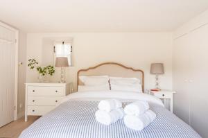 a white bedroom with a bed with towels on it at The Lodge in Bath