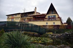 a house on a bridge over a pond in front of a building at Penzión Koruna in Nitrianske Rudno
