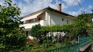 ein weißes Haus mit einem grünen Zaun und Blumen in der Unterkunft Tanja in Opatija