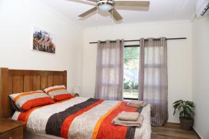 Lodge Huge Dassie في بيلا بيلا: غرفة نوم بسرير ومروحة سقف