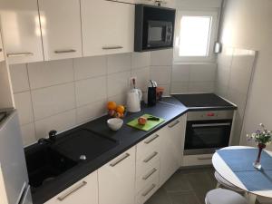 Una cocina con gabinetes blancos y una encimera negra. en La Fontana, en Belgrado