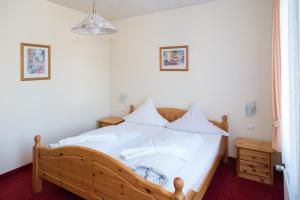 1 dormitorio con cama de madera con sábanas y almohadas blancas en Hotel-Burghagen en Langelsheim