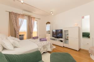 biała sypialnia z łóżkiem i telewizorem w obiekcie City Central Apartments Silva w Makarskiej