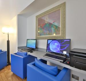 a room with a desk with a computer and blue chairs at c-hotels Atlantic in Milan