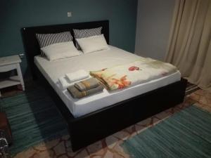 een bed met een zwart frame met handdoeken erop bij TS-George's apartments by the airport in Markopoulon