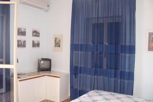 1 dormitorio con cortina azul y TV en B&B Ilys, en Cava deʼ Tirreni