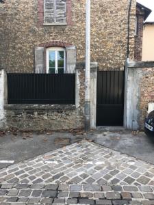 a brick building with a gate and a window at JOLIE PETITE MAISON in Villepinte