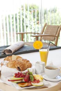 a table with a plate of bread and fruit and a cup of coffee at Alenti Sitges Hotel & Restaurant in Sitges