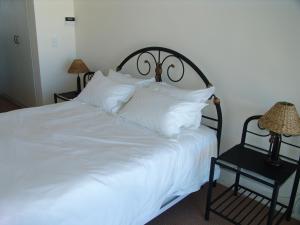 a large white bed with white pillows on it at Bradclin Beach Blouberg in Big Bay