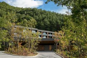 a building in front of a mountain with trees at Fufu Kawaguchiko in Fujikawaguchiko