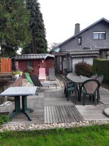 een patio met tafels en stoelen op een houten terras bij Le chalet d Egide in Waimes