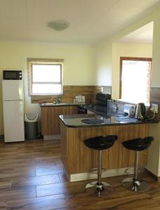 a kitchen with a counter and two bar stools at Lodge Huge Dassie in Bela-Bela