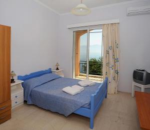 1 dormitorio con cama azul y balcón en Villa Magemenou, en Nikiana