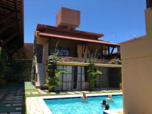 a group of people in a swimming pool in front of a house at Apartamentos Condominio a Beira Mar in Cabo de Santo Agostinho