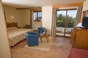 a bedroom with a bed and a tv and a window at Hotel Alcadima in Lanjarón