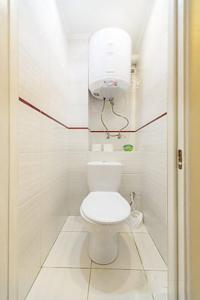 La salle de bains est pourvue de toilettes et d'une lumière sur le mur. dans l'établissement Апартаменты на ул.Героев Днепра, Оболонь, à Kiev