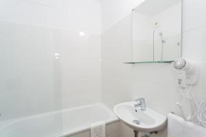 a white bathroom with a sink and a mirror at Hostal Argo in Barcelona