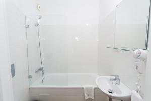 a white bathroom with a sink and a shower at Hostal Argo in Barcelona