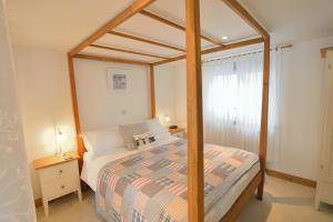 a bedroom with a bed with a wooden canopy at Althea House with parking in Padstow