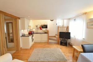 a kitchen with white cabinets and a living room at Althea House with parking in Padstow