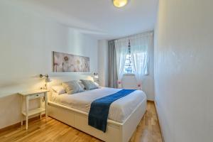 a white bedroom with a bed and a window at Apartamento&piscina cerca de Barcelona in Ripollet