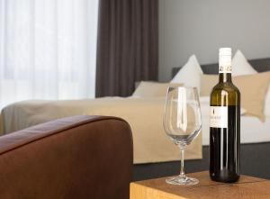 Una botella de vino sentada en una mesa con una copa de vino en anders Kontorhaus Hotel en Lüneburg