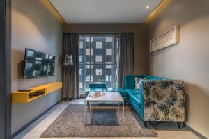 a living room with a blue couch and a tv at Hotel B plus L in Hyderabad