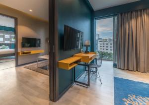 海得拉巴的住宿－Hotel B plus L，一间带书桌和电视的客房以及一间卧室