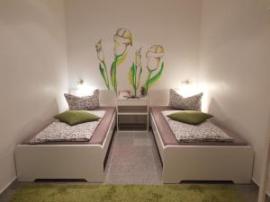 Dos camas en una habitación con una planta en la pared. en Gästeappartements Bierfässl, en Sinsheim