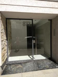 uma porta de vidro de um edifício com uma pessoa refletida nele em Apartamento cómodo y tranquilo con WiFi en Boedo em Buenos Aires