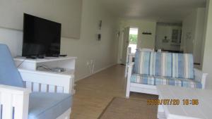 a living room with a flat screen tv and two chairs at The Tides 7 in Struisbaai